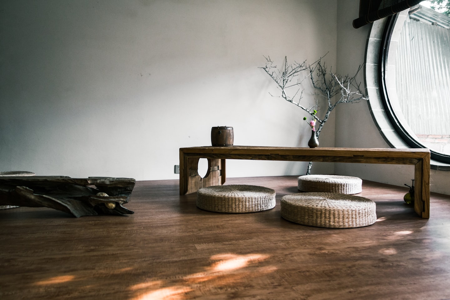 Habitación minimalista con mesa baja de madera y cojines en el suelo.