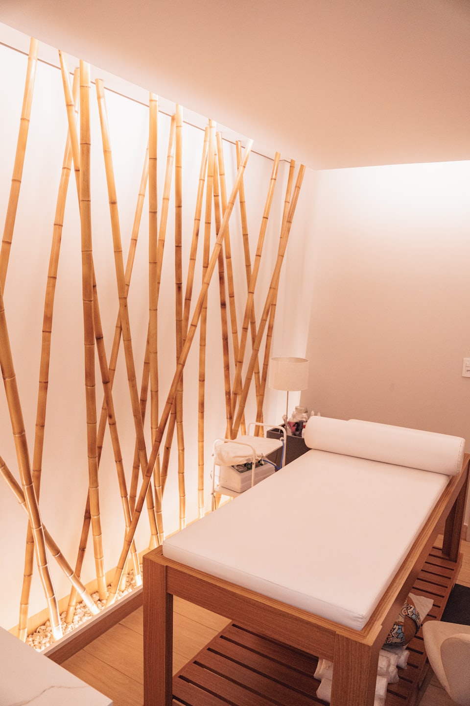 Habitación de spa vacía con pared de bambú y camilla de masaje.